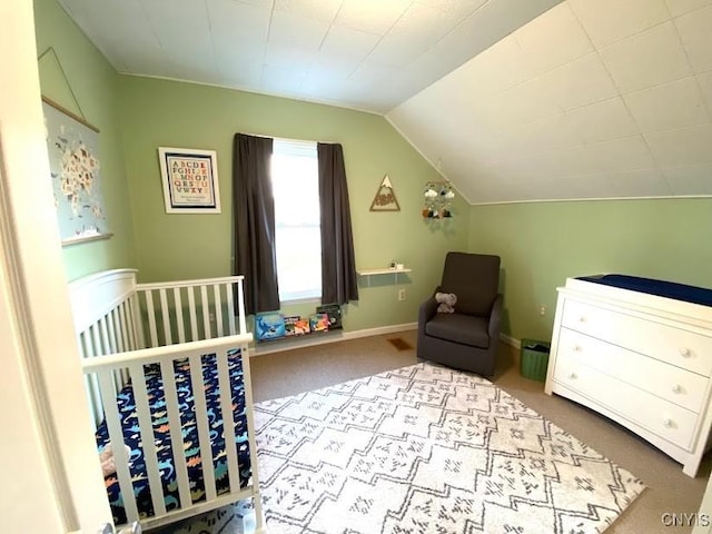 carpeted bedroom featuring a nursery area and lofted ceiling