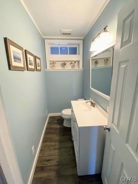 bathroom with crown molding, vanity, wood-type flooring, and toilet