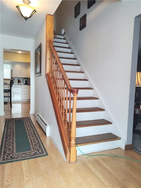 stairs with hardwood / wood-style flooring and a baseboard heating unit