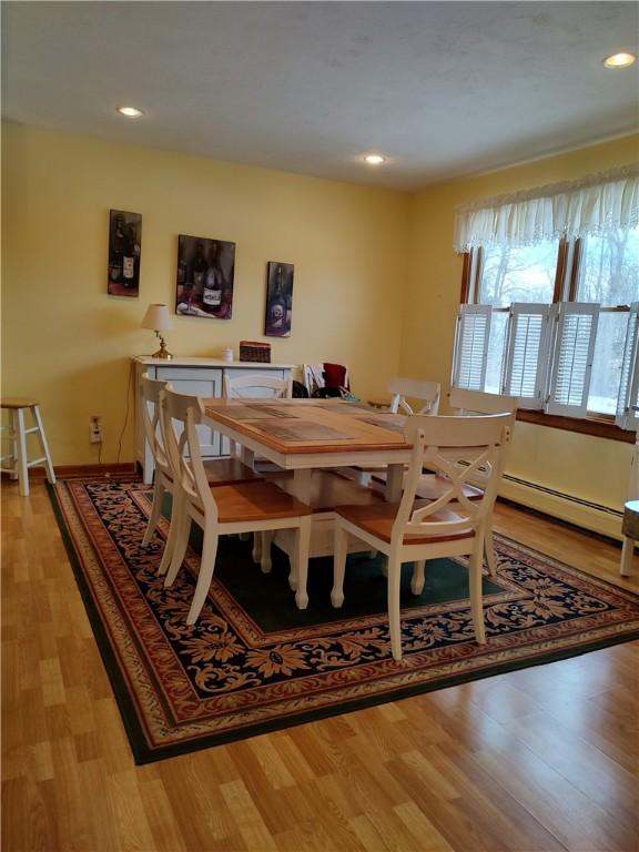 dining area with light wood-type flooring and a baseboard heating unit