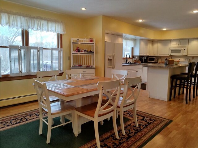 dining space featuring light hardwood / wood-style floors, sink, and a baseboard radiator