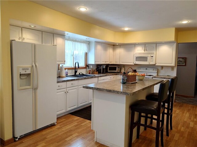 kitchen featuring sink, white cabinets, light hardwood / wood-style floors, and white appliances