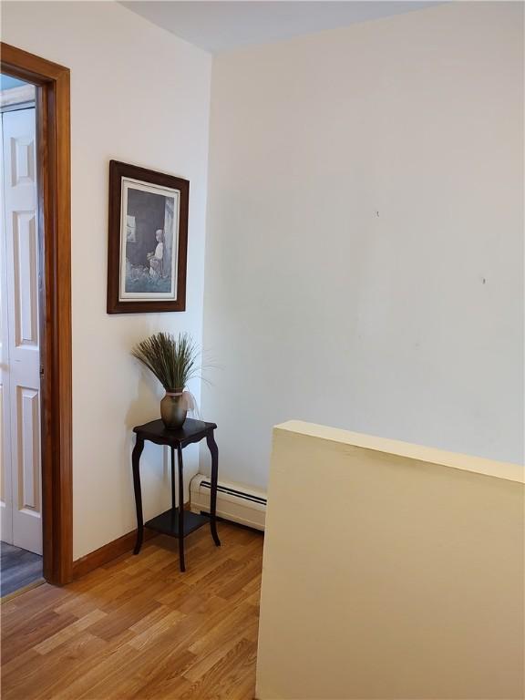 corridor featuring light hardwood / wood-style floors and a baseboard heating unit