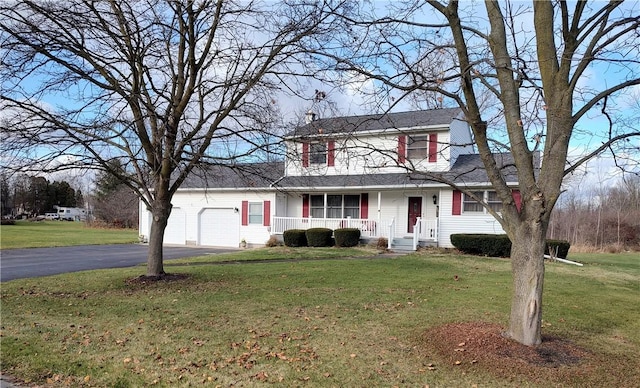 view of front of home featuring covered porch, a garage, and a front lawn