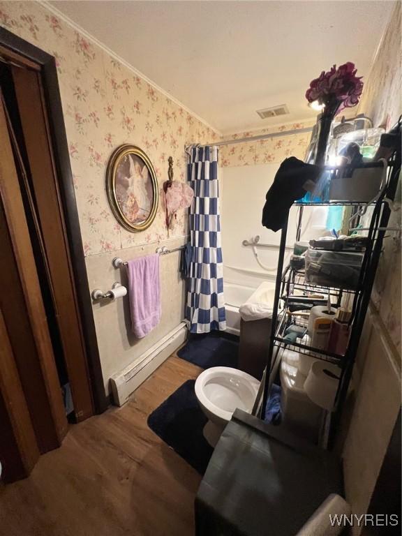 bathroom with shower / tub combo, ornamental molding, a baseboard heating unit, wood-type flooring, and toilet