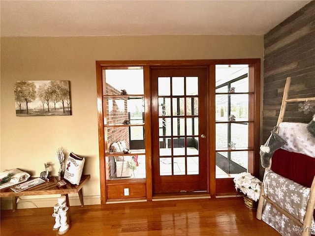 doorway with dark hardwood / wood-style flooring, wooden walls, and french doors