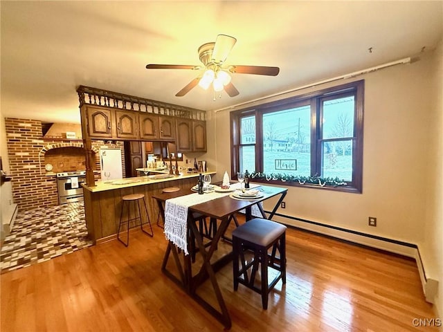 dining room with baseboard heating, ceiling fan, and wood-type flooring