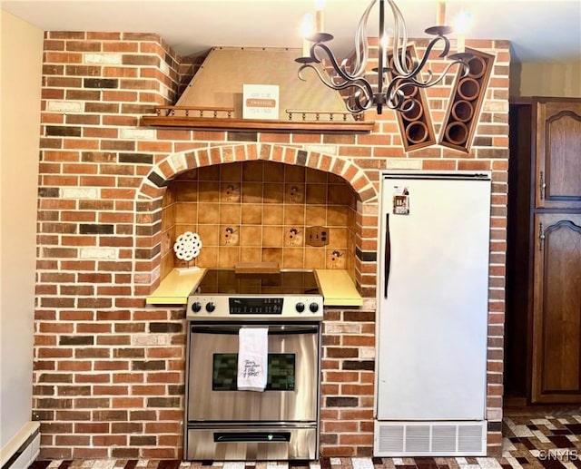 kitchen with stainless steel electric stove, white refrigerator, a baseboard radiator, a chandelier, and hanging light fixtures