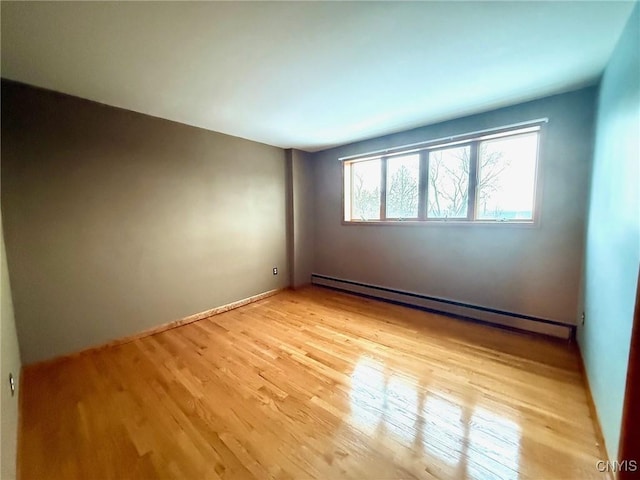 empty room with a baseboard radiator and light hardwood / wood-style floors