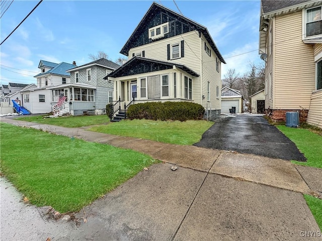 front facade featuring an outdoor structure, a garage, central air condition unit, and a front lawn