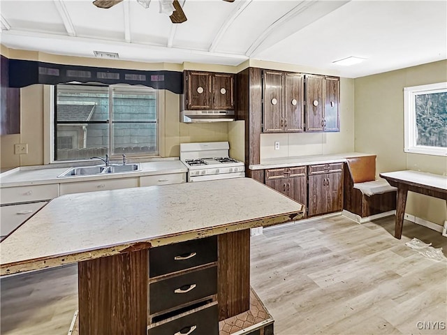 kitchen with a center island, sink, ceiling fan, light wood-type flooring, and white gas stove