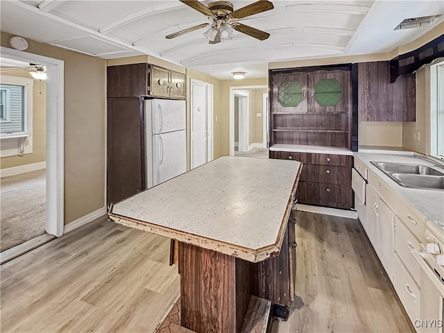 kitchen featuring ceiling fan, sink, a center island, white refrigerator, and light wood-type flooring