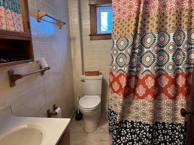 full bathroom with toilet, curtained shower, tile walls, and vanity