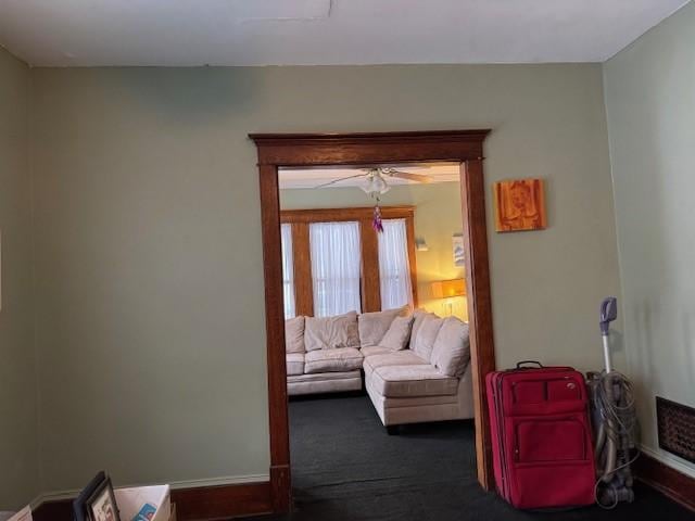 living area featuring baseboards and dark colored carpet