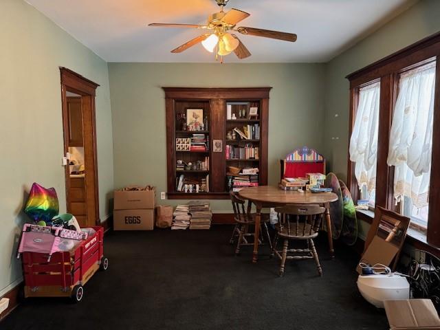 carpeted dining area with ceiling fan