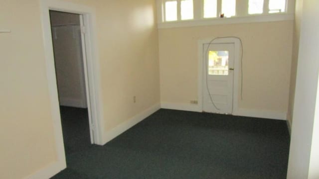 entrance foyer featuring baseboards and dark carpet