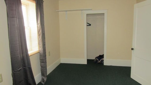 empty room featuring baseboards and dark carpet