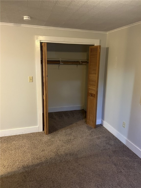 unfurnished bedroom featuring a textured ceiling, a closet, carpet floors, crown molding, and baseboards