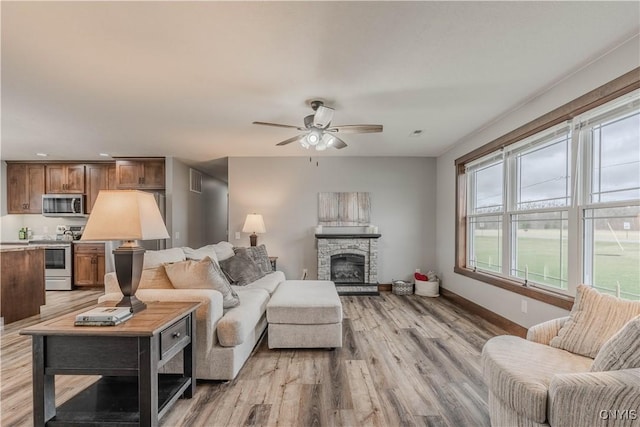 living room with a fireplace, light hardwood / wood-style floors, and ceiling fan