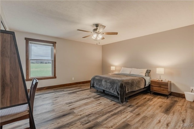 bedroom with ceiling fan, light hardwood / wood-style floors, and a textured ceiling