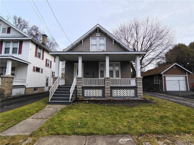 bungalow featuring an outbuilding, a front lawn, a porch, and a garage