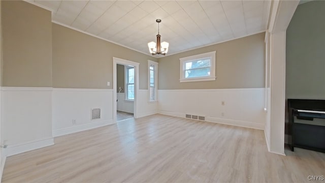 unfurnished dining area featuring a notable chandelier, light wood-type flooring, and ornamental molding