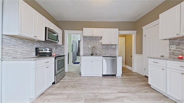 kitchen with backsplash, white cabinets, and appliances with stainless steel finishes