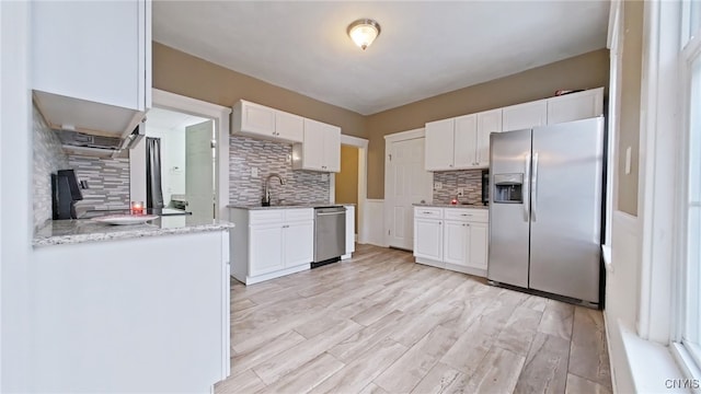 kitchen with decorative backsplash, light hardwood / wood-style flooring, white cabinets, and stainless steel appliances