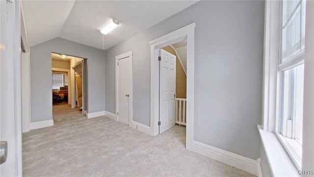 hallway featuring light carpet and vaulted ceiling