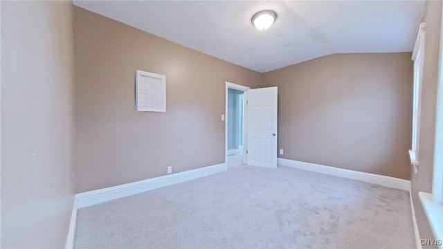 carpeted spare room featuring lofted ceiling