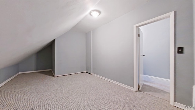 bonus room with light colored carpet and vaulted ceiling