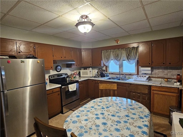 kitchen featuring decorative backsplash, appliances with stainless steel finishes, a paneled ceiling, sink, and light tile patterned floors