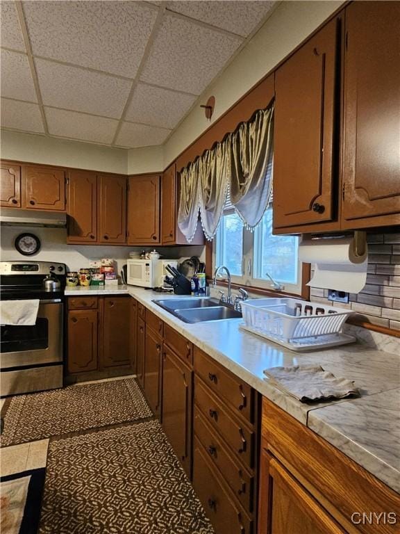 kitchen with decorative backsplash, a paneled ceiling, stainless steel range with electric cooktop, and sink