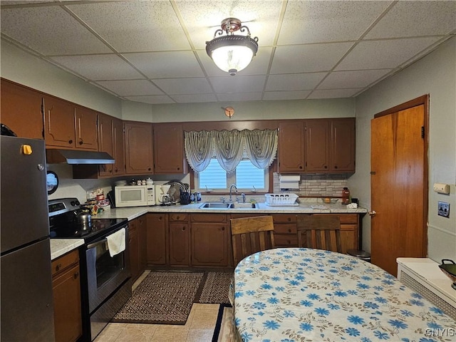 kitchen with sink, a drop ceiling, tasteful backsplash, light tile patterned flooring, and appliances with stainless steel finishes