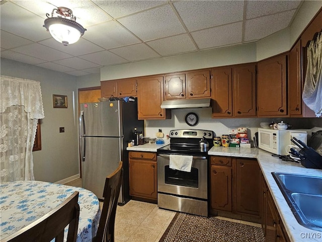 kitchen featuring a paneled ceiling, sink, light tile patterned floors, and appliances with stainless steel finishes