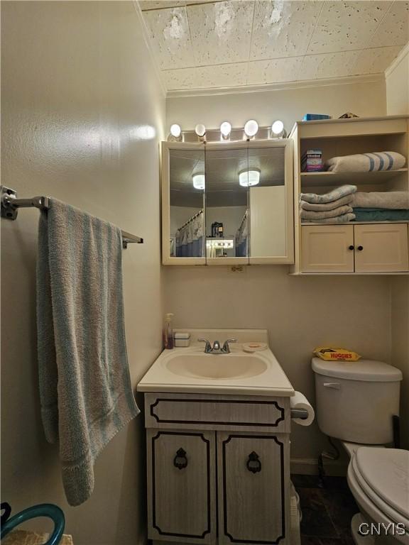 bathroom featuring toilet, vanity, and ornamental molding