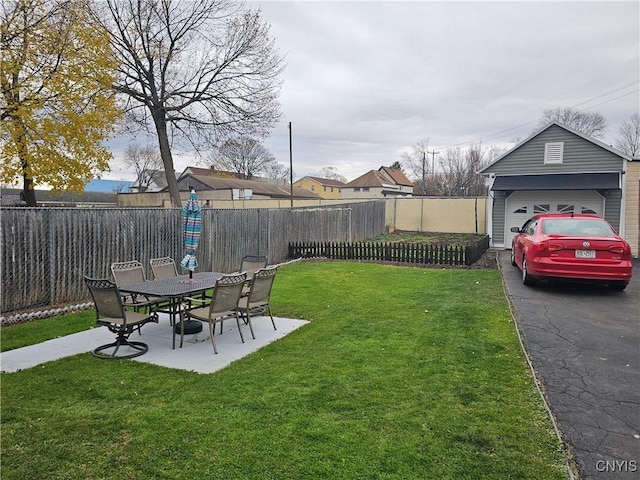 view of yard with a garage, a patio area, and an outbuilding