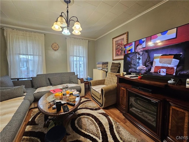 living room featuring radiator heating unit, light hardwood / wood-style floors, an inviting chandelier, and crown molding