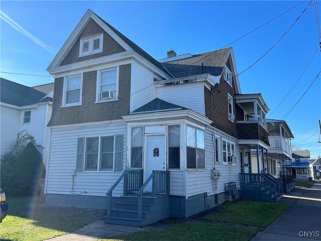 view of front of home with a balcony, a chimney, and a shingled roof