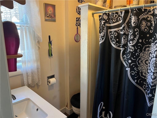 bathroom featuring a shower with curtain, toilet, and a sink