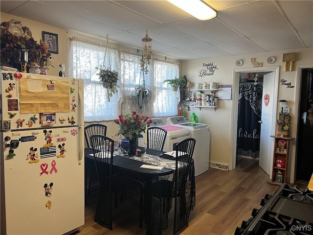 dining space with a drop ceiling, washer and dryer, and wood-type flooring