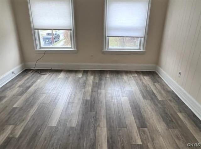 empty room with dark wood-style floors, baseboards, and a wealth of natural light