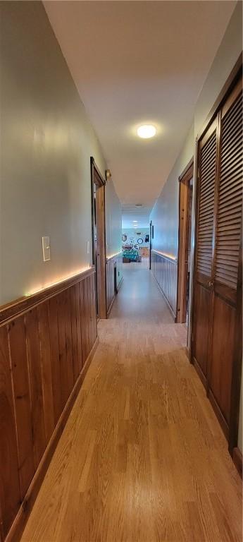 hall with light hardwood / wood-style floors and wood walls