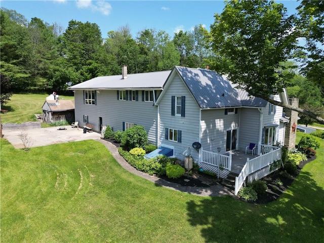 back of house featuring a wooden deck, a patio area, and a yard