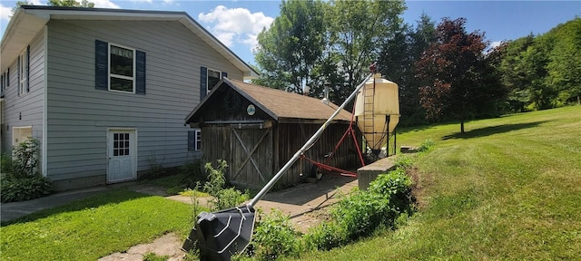 back of property featuring a lawn and an outdoor structure