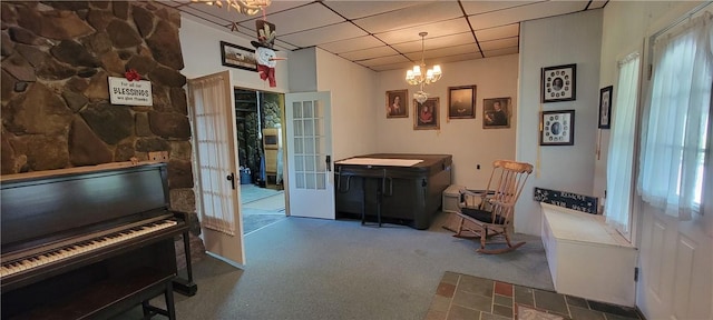 misc room with a notable chandelier, a drop ceiling, a wealth of natural light, and french doors