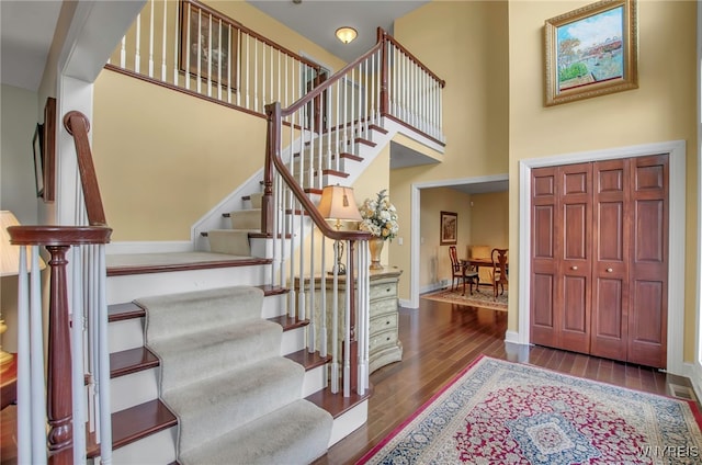 foyer entrance with a towering ceiling and dark hardwood / wood-style floors