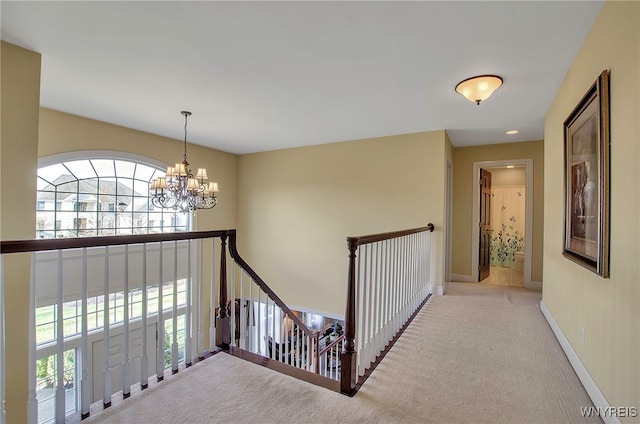 hall featuring light colored carpet and a notable chandelier