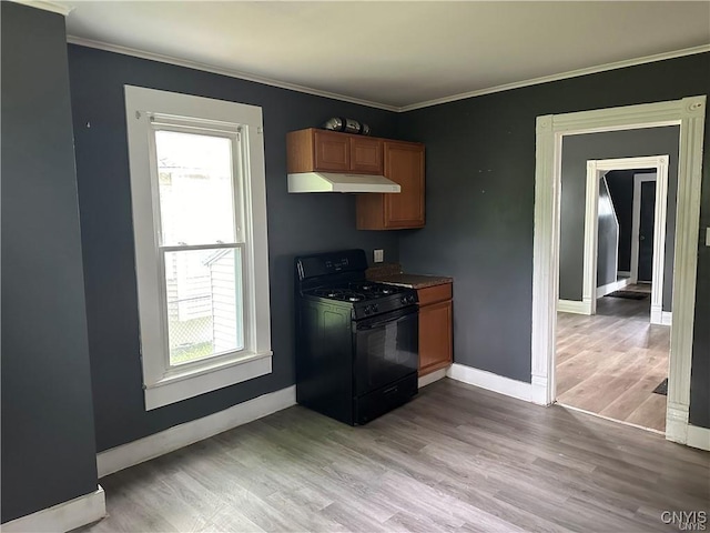 kitchen with gas stove, ornamental molding, and light wood-type flooring