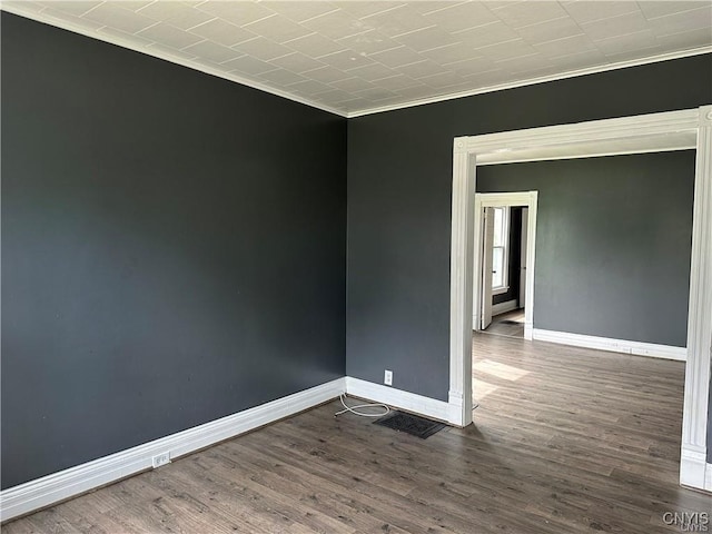 empty room with crown molding and dark hardwood / wood-style flooring